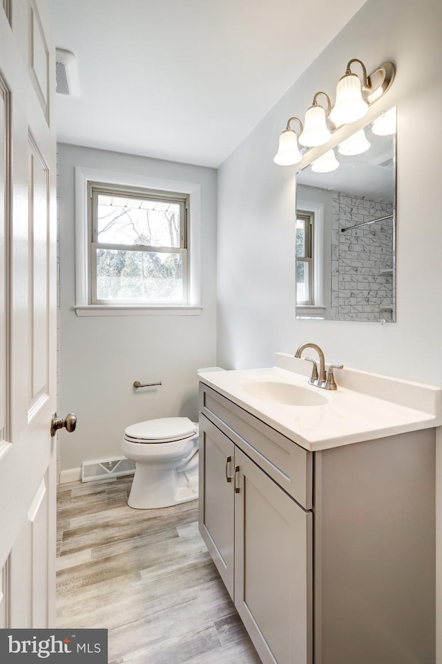 bathroom featuring visible vents, toilet, wood finished floors, and vanity