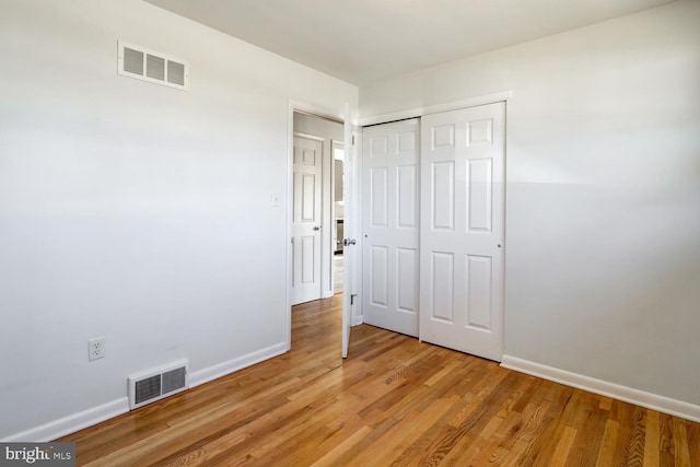 unfurnished bedroom featuring visible vents, baseboards, a closet, and light wood finished floors