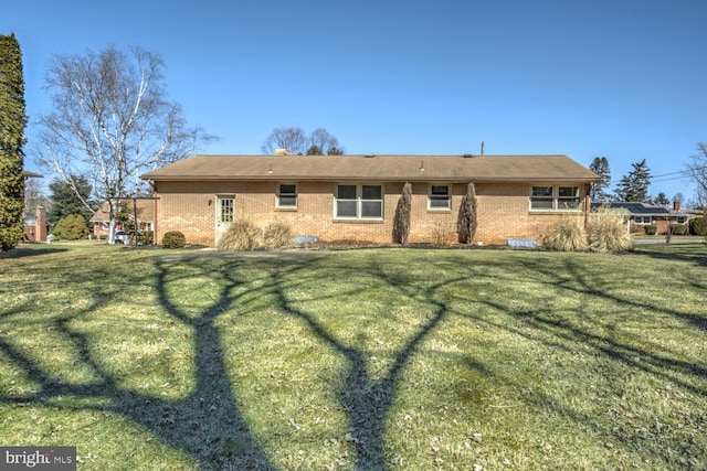 rear view of house featuring a yard and brick siding