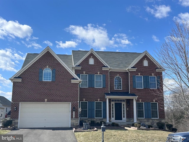view of front of home with brick siding, driveway, a front yard, and a garage