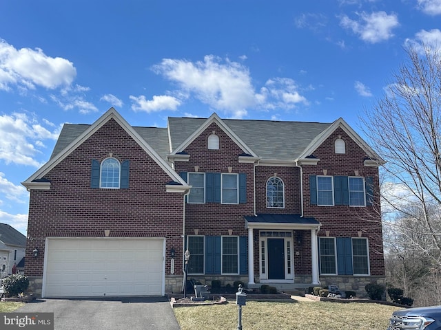 view of front of home with a front lawn, brick siding, driveway, and an attached garage