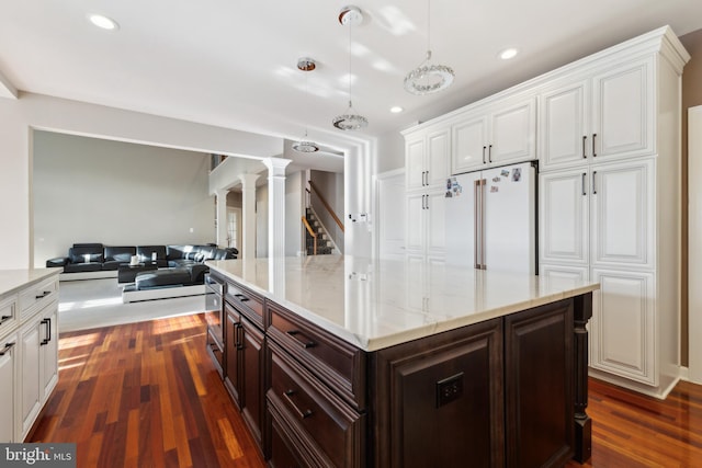 kitchen with dark wood-type flooring, high end fridge, open floor plan, and white cabinetry