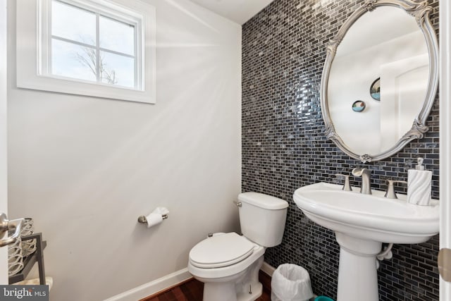half bathroom with baseboards and toilet