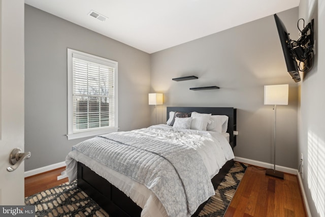 bedroom with wood finished floors, visible vents, and baseboards
