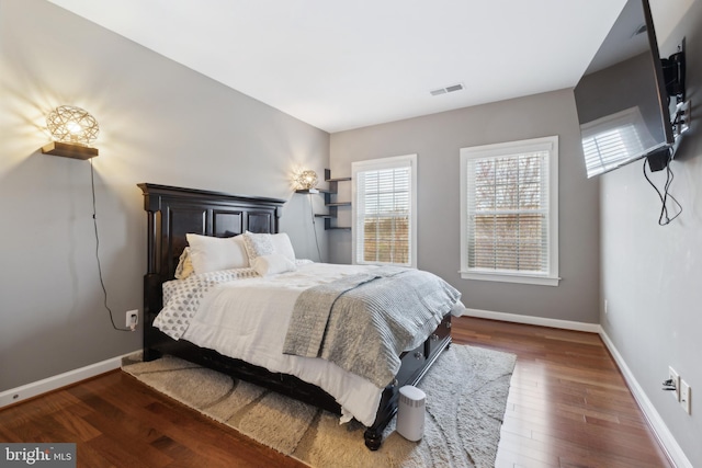 bedroom with visible vents, baseboards, and wood finished floors
