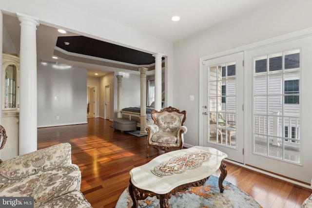 living room featuring decorative columns, wood finished floors, and recessed lighting