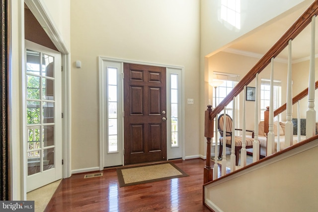 entryway featuring visible vents, stairway, a high ceiling, and wood finished floors