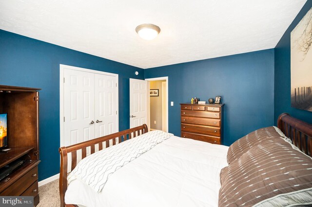 carpeted bedroom featuring baseboards and a closet