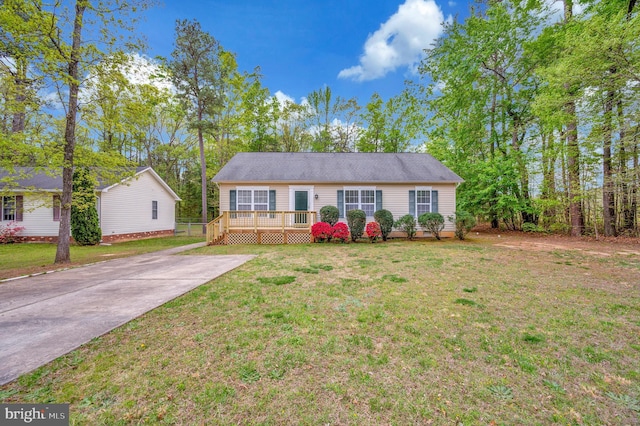ranch-style home with a wooden deck, driveway, and a front lawn
