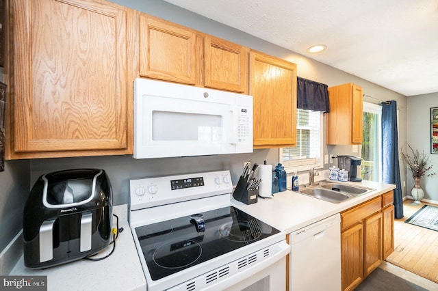 kitchen featuring light countertops, recessed lighting, a sink, and white appliances
