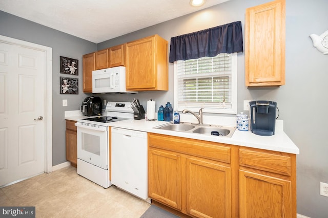 kitchen featuring baseboards, light countertops, white appliances, and a sink
