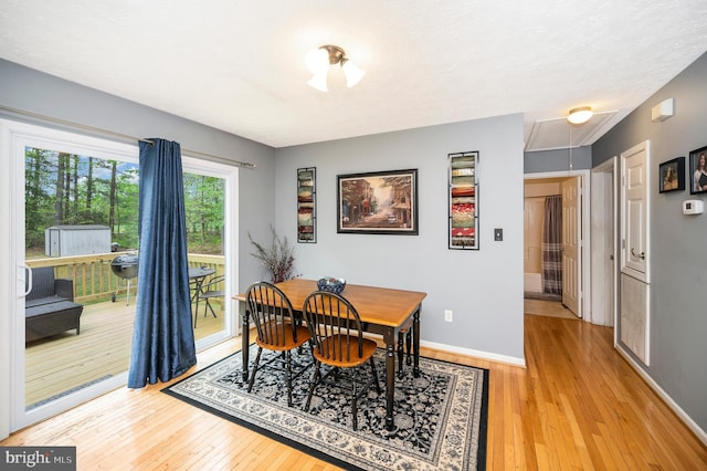 dining area featuring attic access, hardwood / wood-style flooring, and baseboards