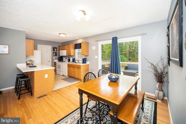 dining area with light wood-style floors, visible vents, and baseboards