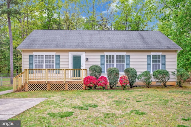 view of front of house featuring a wooden deck, roof with shingles, and a front lawn