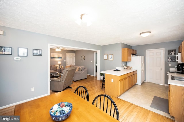 dining area featuring a textured ceiling, light wood finished floors, and baseboards