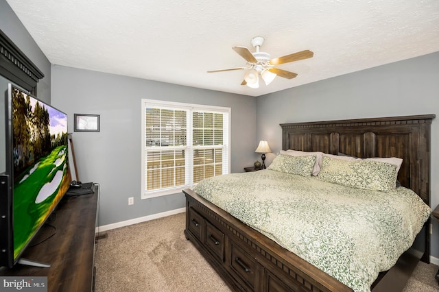 bedroom with light colored carpet, ceiling fan, baseboards, and a textured ceiling