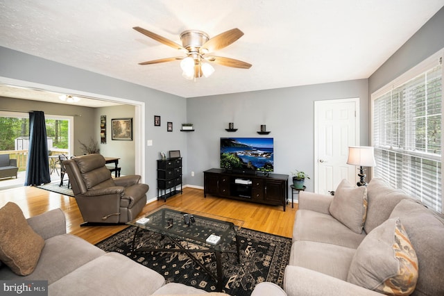 living room featuring ceiling fan, baseboards, and wood finished floors