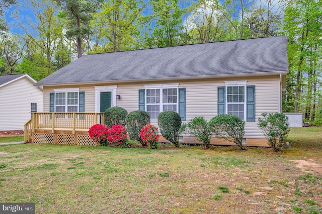 view of front of property with a deck, a shingled roof, and a front yard