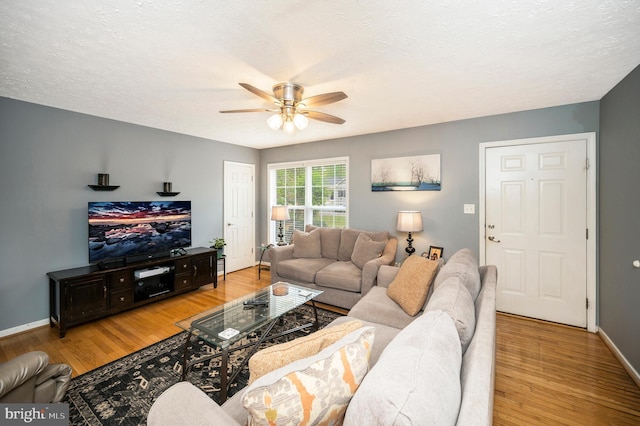 living room with baseboards, a ceiling fan, and light wood finished floors