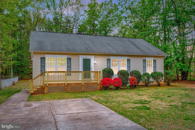 ranch-style home with a wooden deck, a patio, a shingled roof, and a front lawn