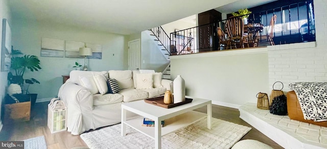 living area featuring baseboards, wood finished floors, and stairs