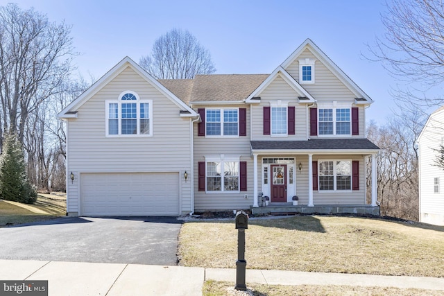 traditional home with a garage, driveway, a shingled roof, and a front yard