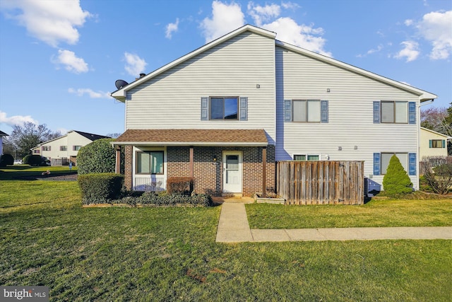 exterior space with a yard, brick siding, and fence