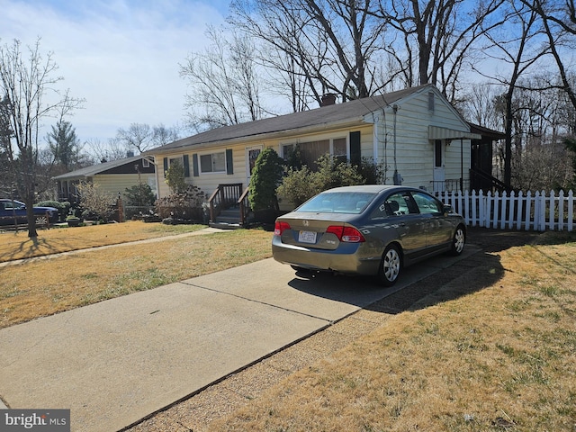 ranch-style house with concrete driveway, a chimney, a front yard, and fence