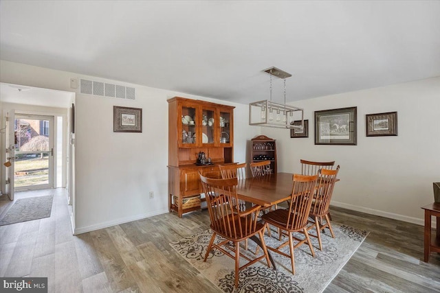 dining area featuring visible vents, baseboards, and wood finished floors