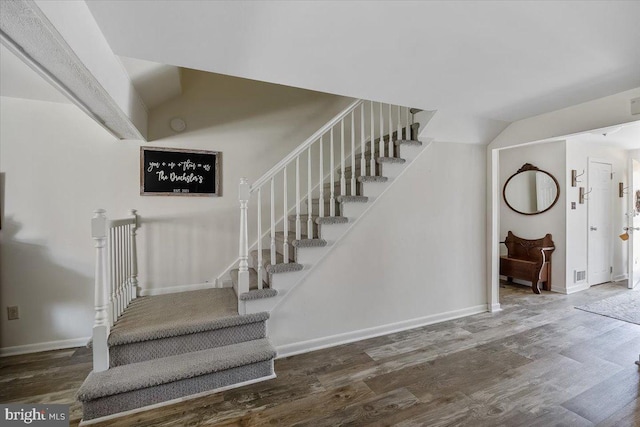 stairs with baseboards, wood finished floors, and vaulted ceiling