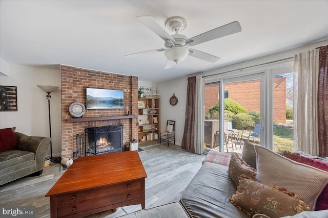 living area featuring a ceiling fan, wood finished floors, and a fireplace