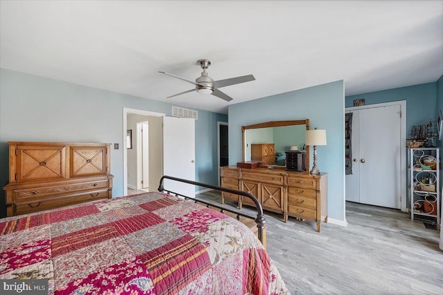 bedroom featuring ceiling fan, visible vents, baseboards, and light wood-style flooring