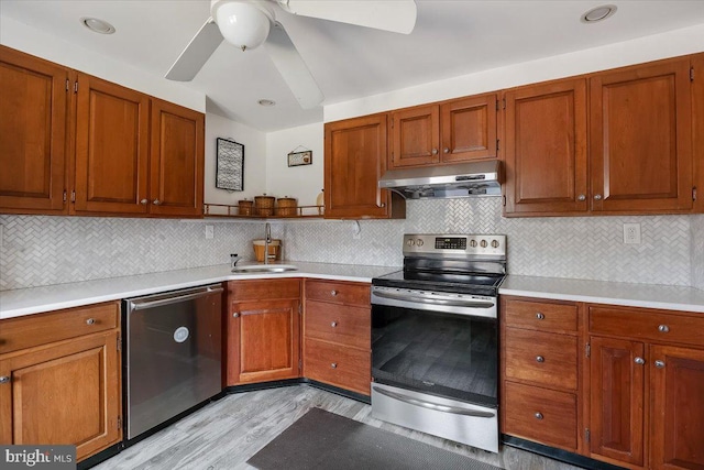 kitchen featuring under cabinet range hood, a sink, stainless steel appliances, light countertops, and ceiling fan