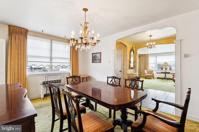 dining space featuring a wealth of natural light, arched walkways, a chandelier, and radiator heating unit