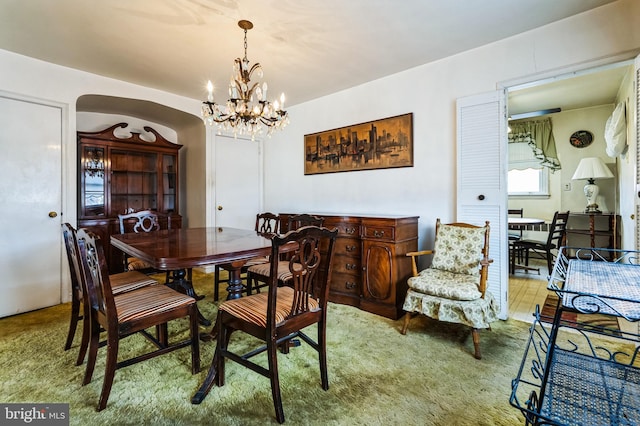 dining area with arched walkways and a notable chandelier