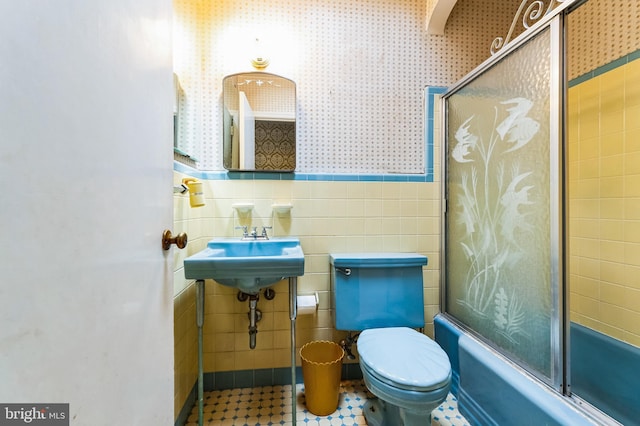 full bath featuring a wainscoted wall, enclosed tub / shower combo, wallpapered walls, tile walls, and toilet