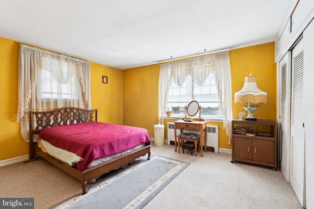 carpeted bedroom with a closet, baseboards, and radiator