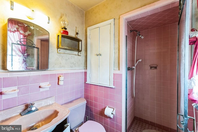 bathroom with wallpapered walls, a shower stall, toilet, and a wainscoted wall