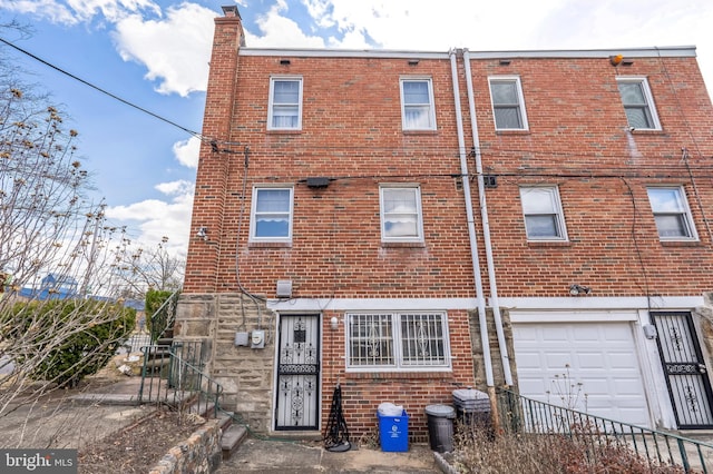 rear view of property featuring brick siding, an attached garage, a chimney, and fence