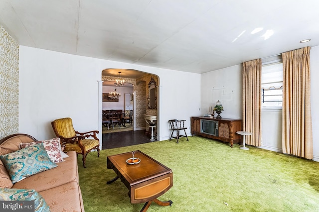 carpeted living area with arched walkways and a notable chandelier