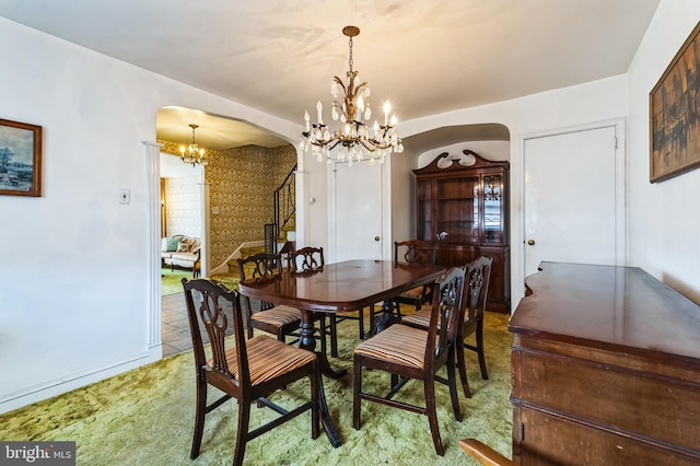 dining area featuring stairway, arched walkways, and a chandelier