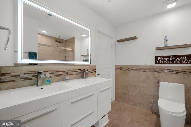 full bath with double vanity, toilet, tiled shower, and a sink