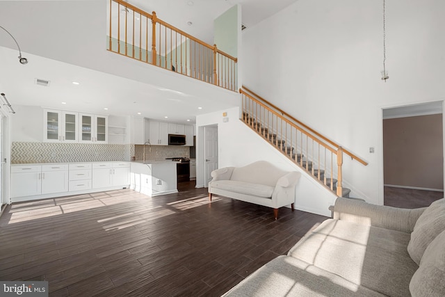 living room with stairway, wood finished floors, visible vents, recessed lighting, and a towering ceiling