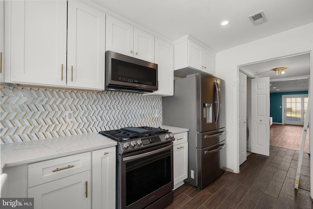 kitchen with visible vents, backsplash, white cabinetry, appliances with stainless steel finishes, and dark wood-style flooring