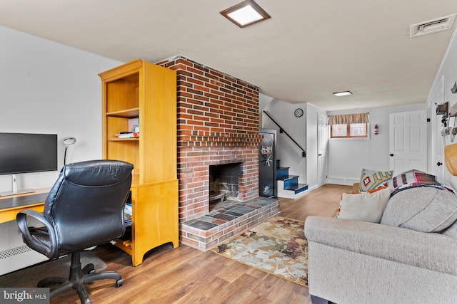 office area with visible vents, a brick fireplace, and wood finished floors