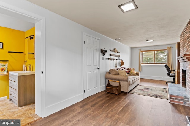 sitting room featuring visible vents, baseboards, wood finished floors, and a fireplace