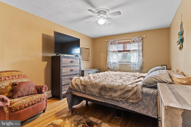 bedroom with a ceiling fan, light wood-type flooring, and baseboard heating