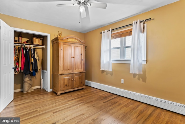 unfurnished bedroom with light wood finished floors, baseboards, a closet, a ceiling fan, and a baseboard radiator