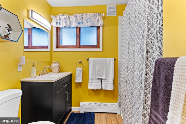 bathroom featuring vanity, wood finished floors, visible vents, toilet, and baseboard heating