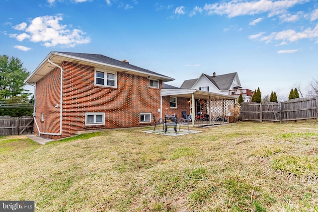 rear view of house with a yard, a patio, brick siding, and a fenced backyard